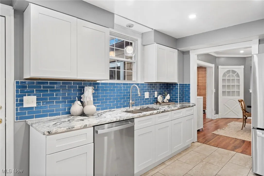Kitchen with sink, white cabinetry, stainless steel appliances, and light hardwood / wood-style floors