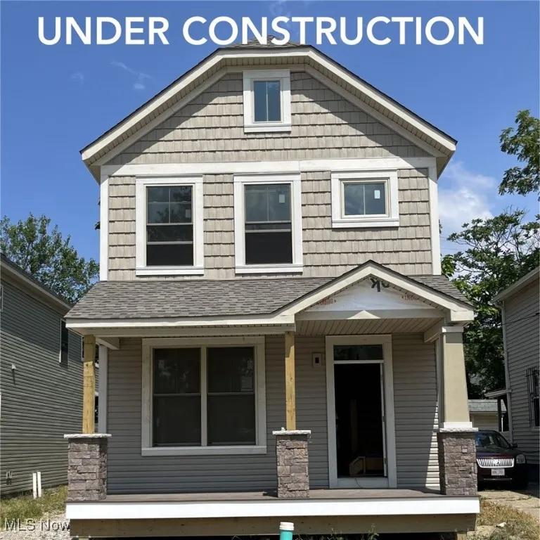 View of front of home with covered porch and roof with shingles