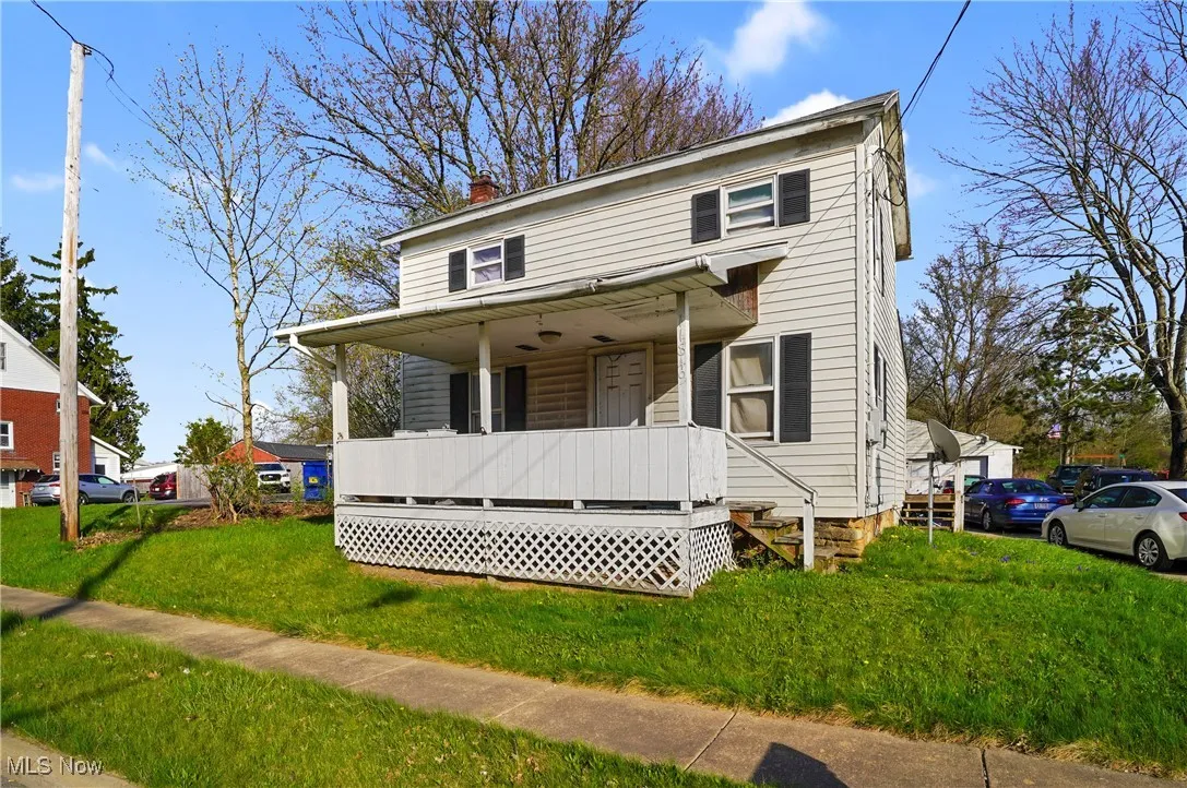View of front of house featuring covered porch, a chimney, and a front lawn