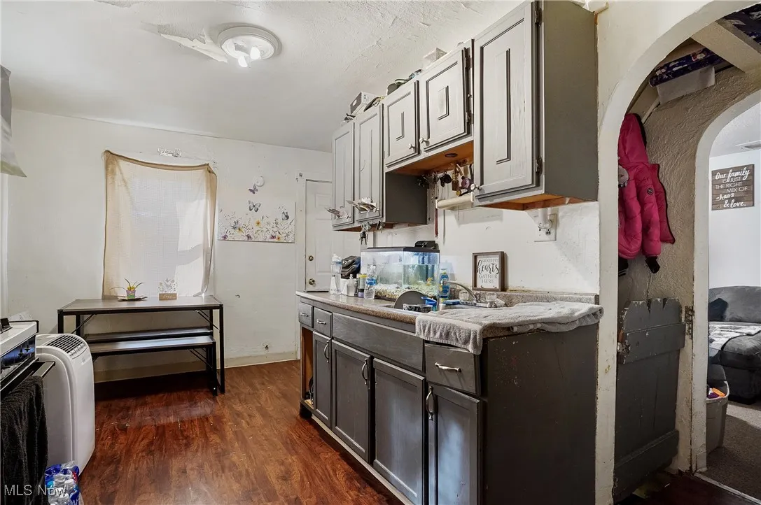 Kitchen featuring dark wood-style flooring, light countertops, and arched walkways