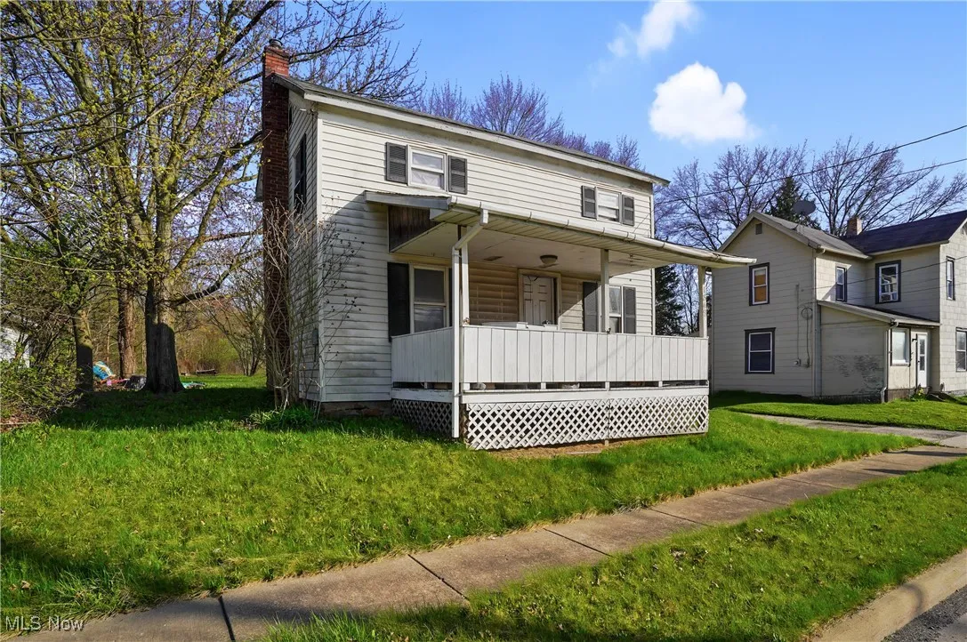 Traditional-style house with a front yard, covered porch, and a chimney