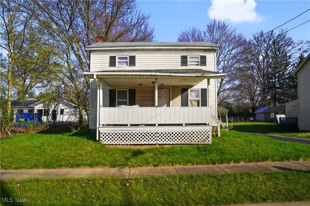 View of front of house with covered porch, a chimney, and a front lawn