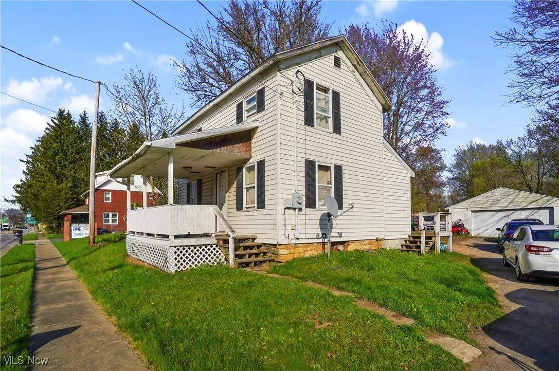 View of property exterior with a lawn, covered porch, and a garage