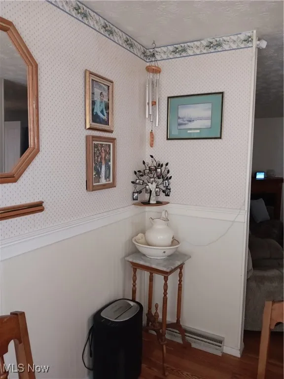 Room details with wood finished floors, a wainscoted wall, and wallpapered walls