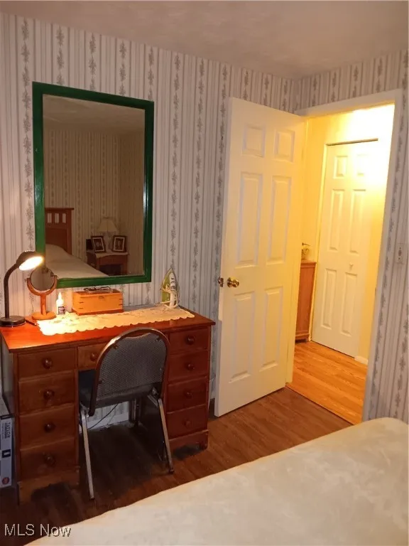 Office area featuring wood finished floors and wallpapered walls