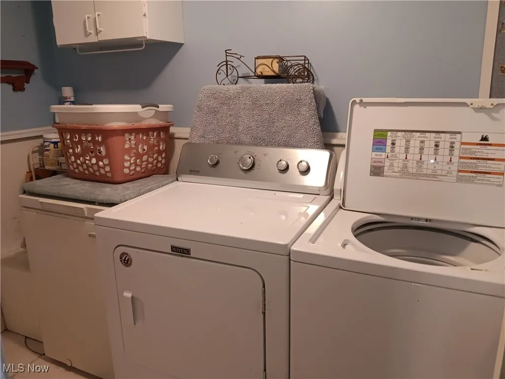 Clothes washing area featuring washer and clothes dryer and cabinet space