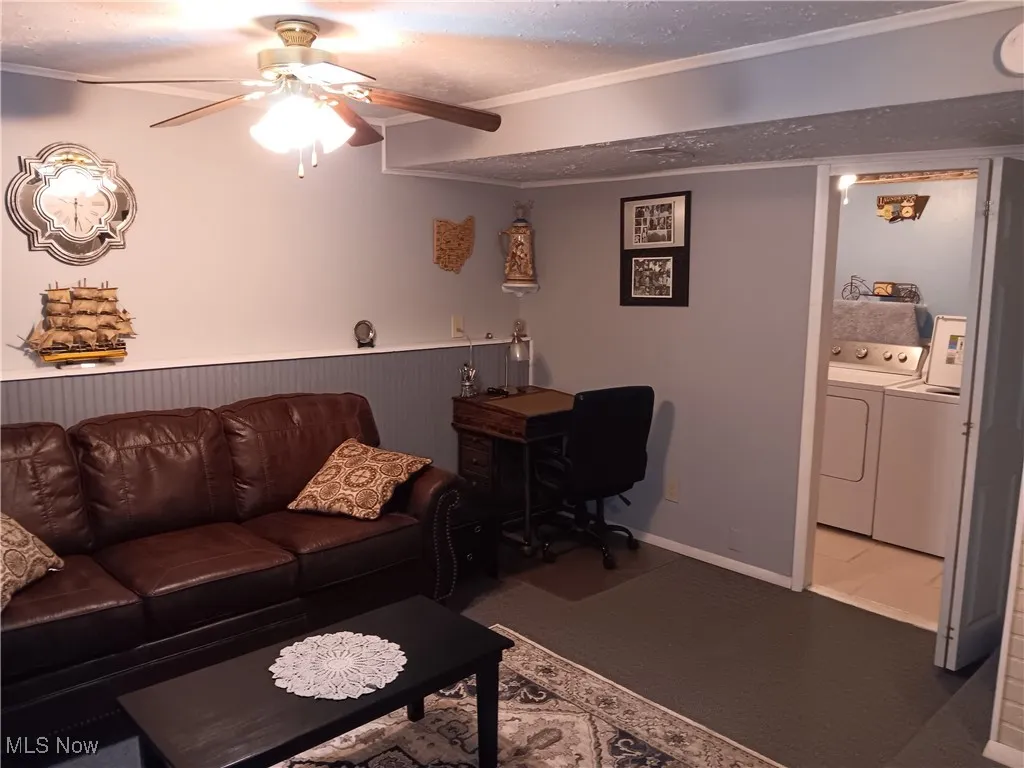 Living area featuring independent washer and dryer, a ceiling fan, crown molding, and a textured ceiling