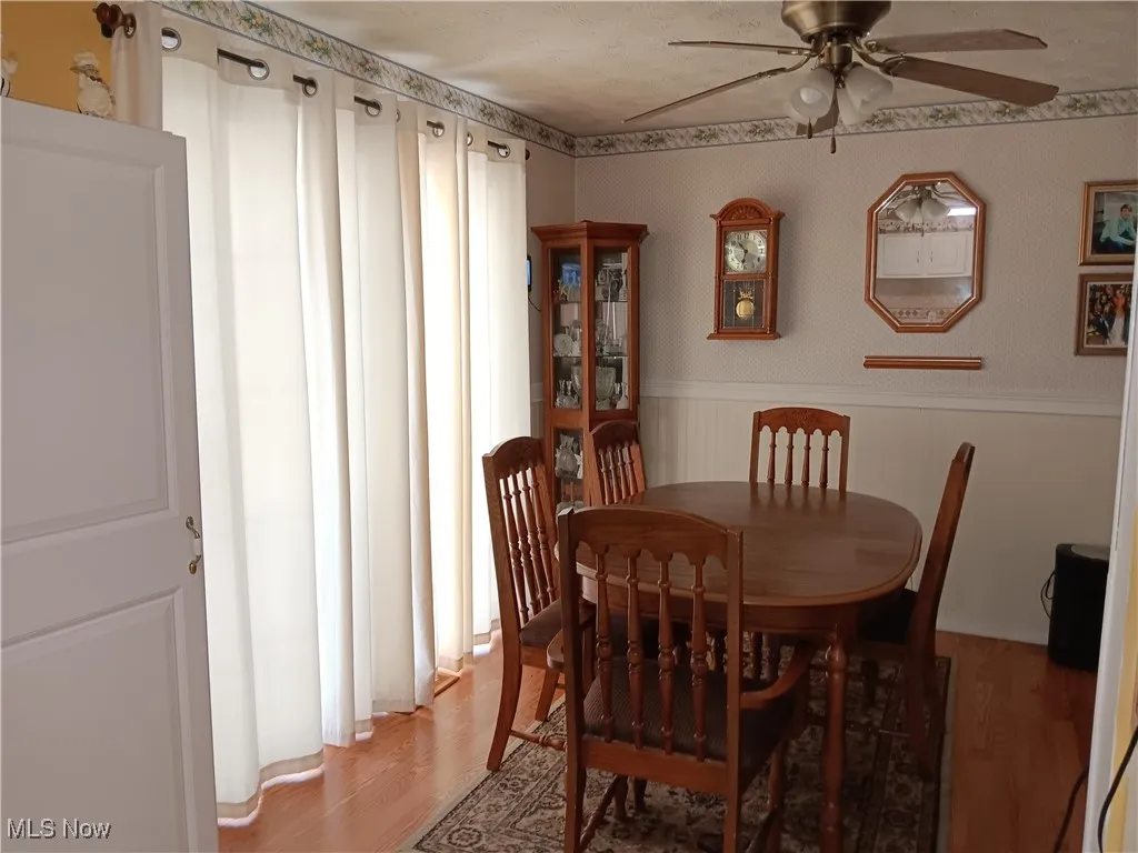 Dining space featuring light wood-style floors, a ceiling fan, and wainscoting