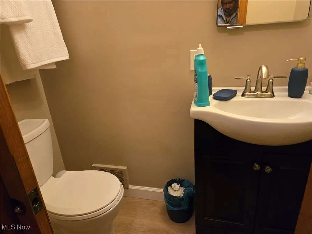 Half bathroom with visible vents, tile patterned flooring, vanity, toilet, and baseboards