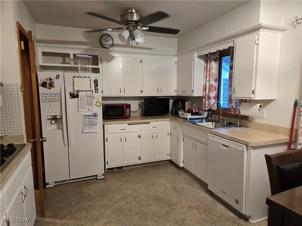 Kitchen featuring white cabinets, ceiling fan, a sink, white appliances, and light countertops