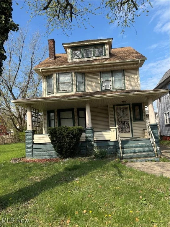 View of front facade featuring covered porch, a chimney, and a front yard