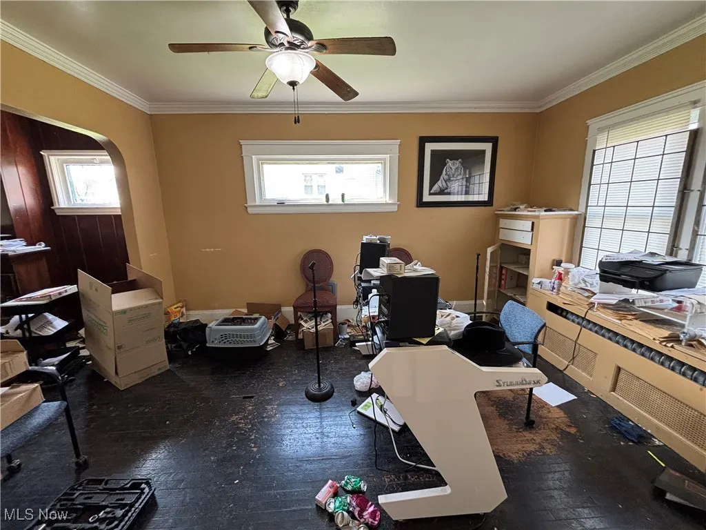 Home office featuring crown molding, arched walkways, a ceiling fan, and hardwood / wood-style flooring