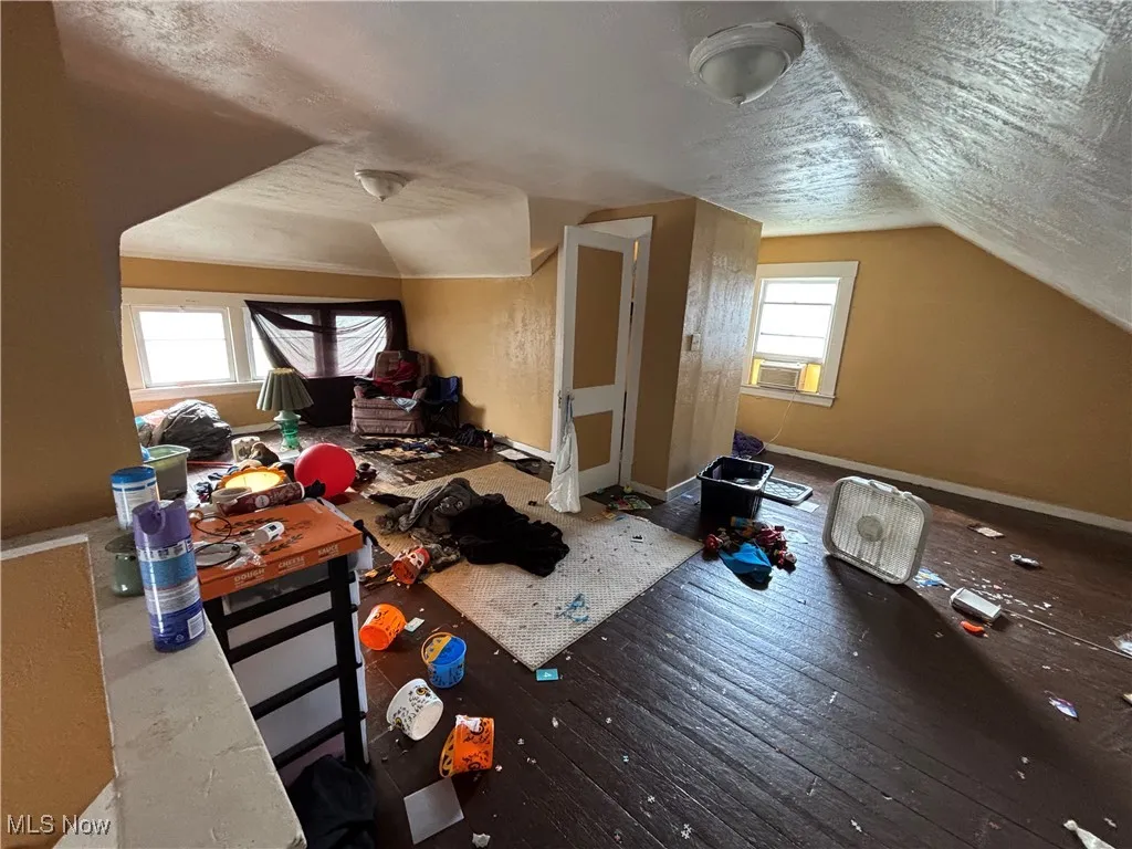 Bonus room featuring baseboards, a textured ceiling, cooling unit, hardwood / wood-style flooring, and vaulted ceiling