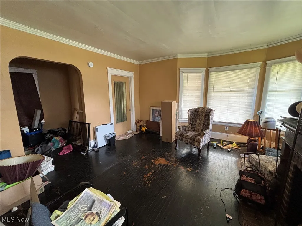 Sitting room featuring crown molding, arched walkways, and hardwood / wood-style flooring