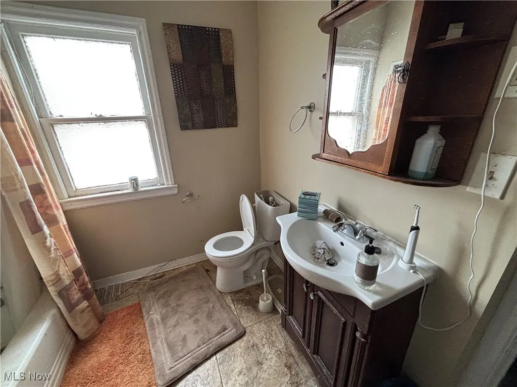 Bathroom with toilet, baseboards, plenty of natural light, and vanity