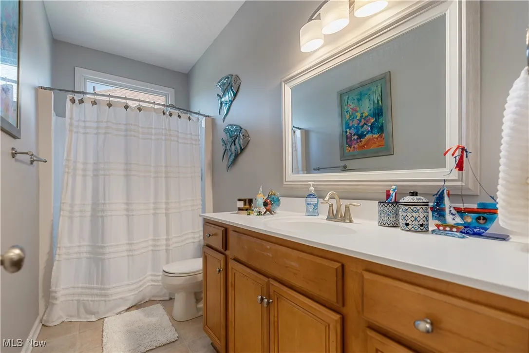 Full bath with toilet, vanity, curtained shower, and tile patterned floors