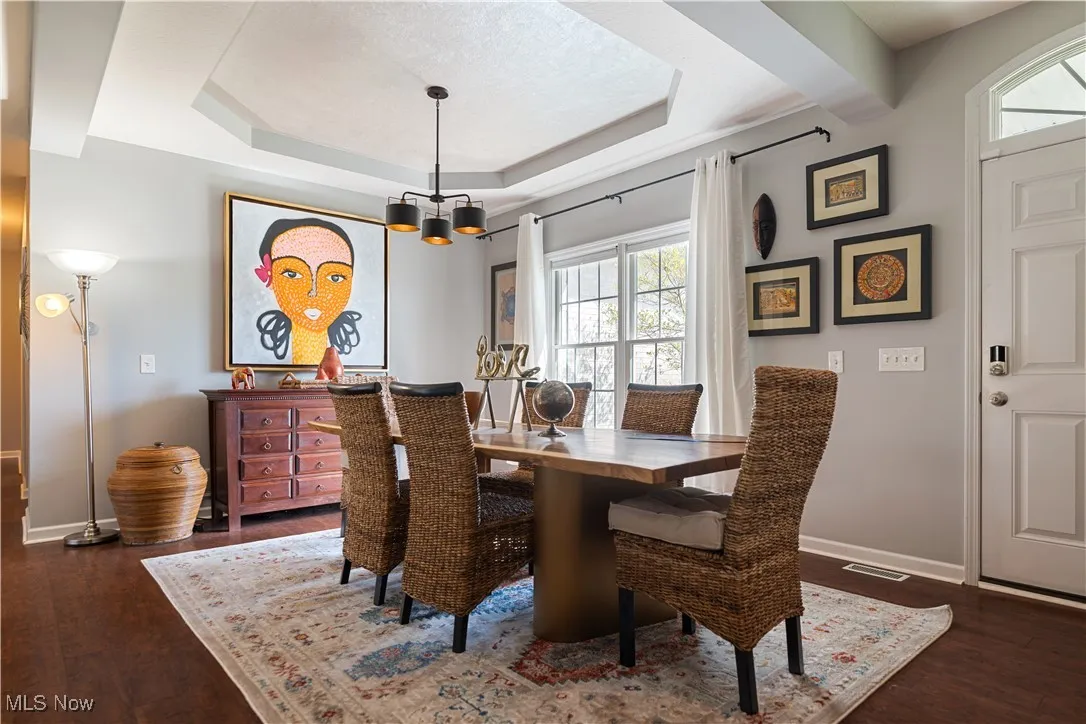Dining space featuring dark wood-type flooring, a chandelier, a healthy amount of sunlight, and baseboards