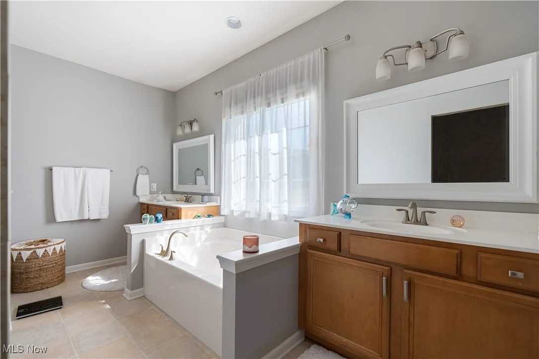 Full bathroom featuring baseboards, tile patterned floors, a garden tub, and vanity
