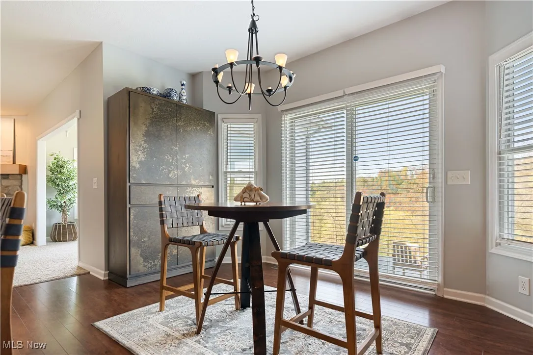 Dining area featuring a healthy amount of sunlight, a notable chandelier, dark wood finished floors, and baseboards
