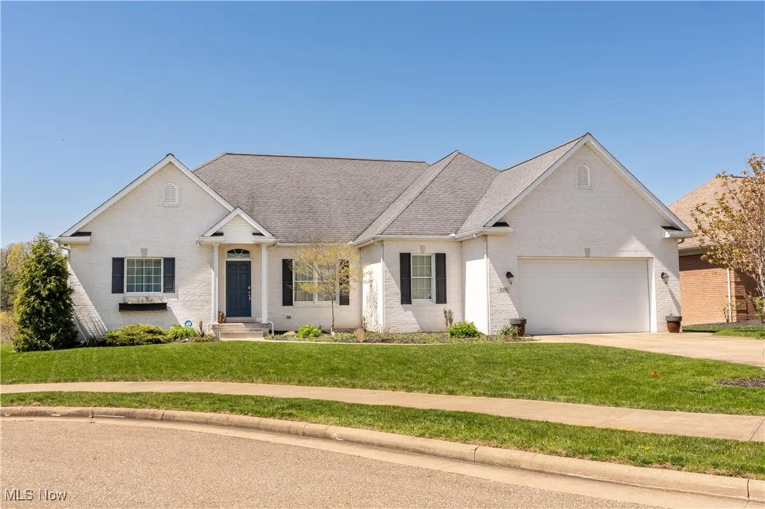 Ranch-style house featuring a garage, brick siding, a front lawn, and driveway