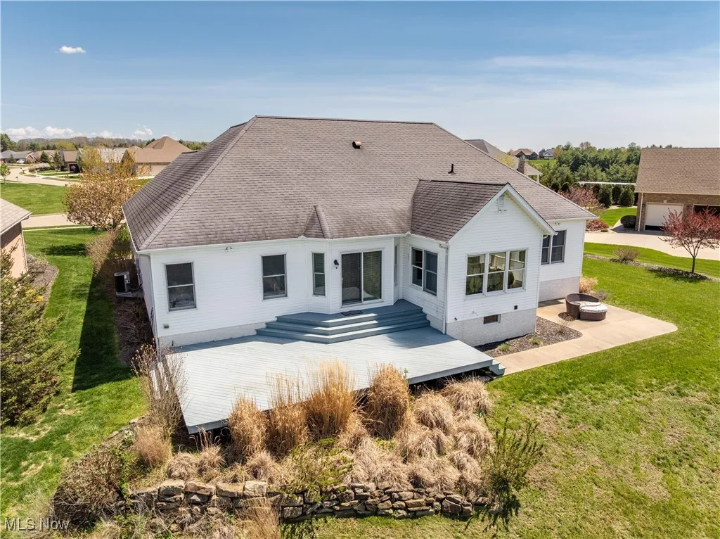 Rear view of house with roof with shingles and a lawn