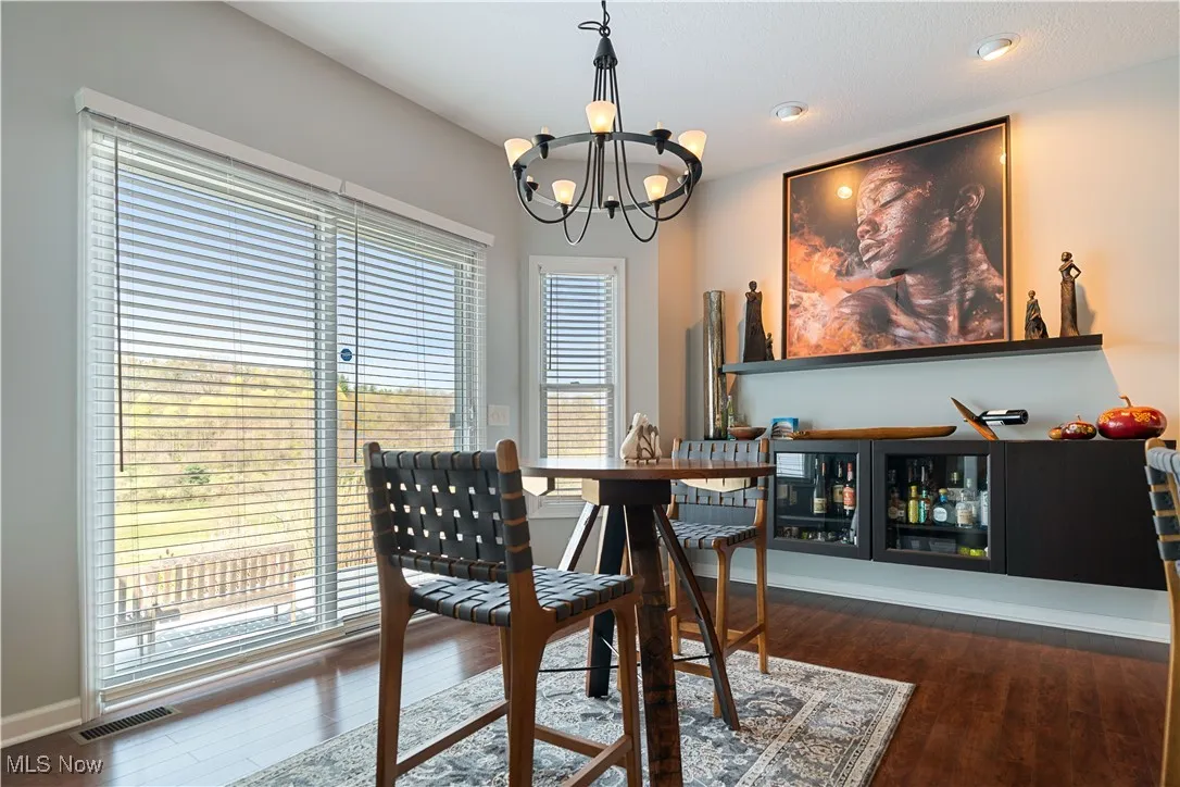 Dining space with a notable chandelier, baseboards, wood finished floors, and visible vents