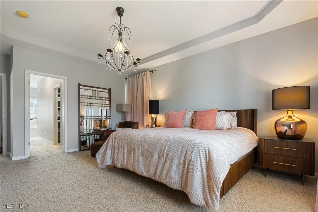Carpeted bedroom with a notable chandelier and baseboards