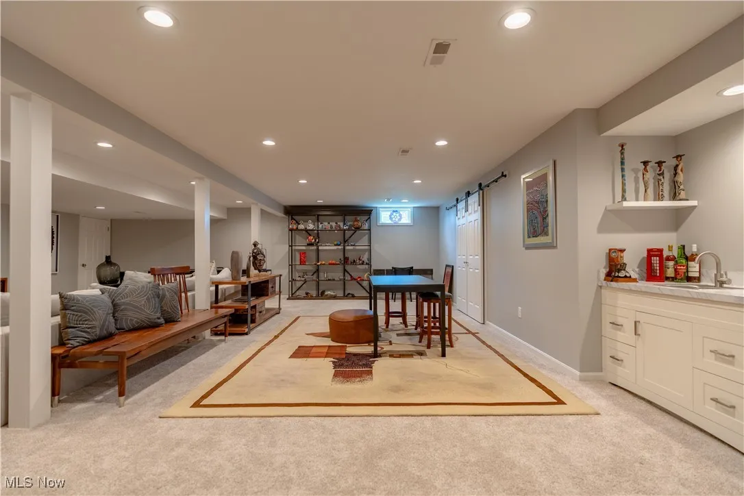 Dining space featuring light colored carpet, a barn door, recessed lighting, and wet bar