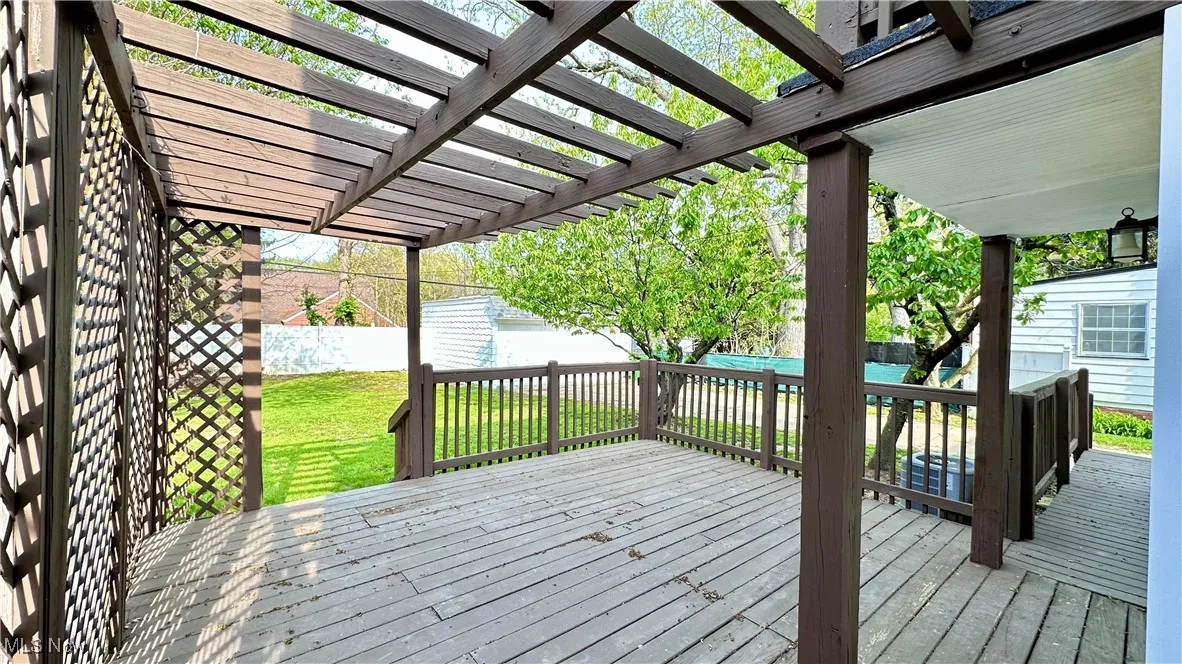 Wooden terrace with a fenced backyard, a yard, and a pergola