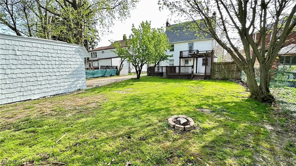 View of yard with fence, a wooden deck, and a fire pit