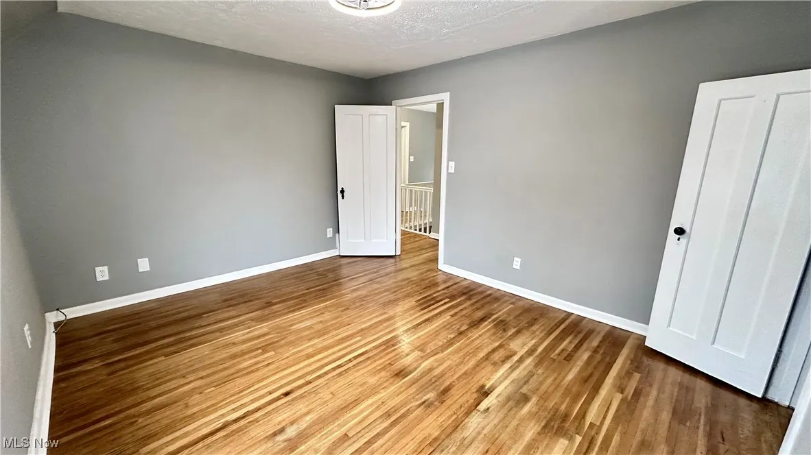 Unfurnished bedroom featuring baseboards, a textured ceiling, and wood finished floors