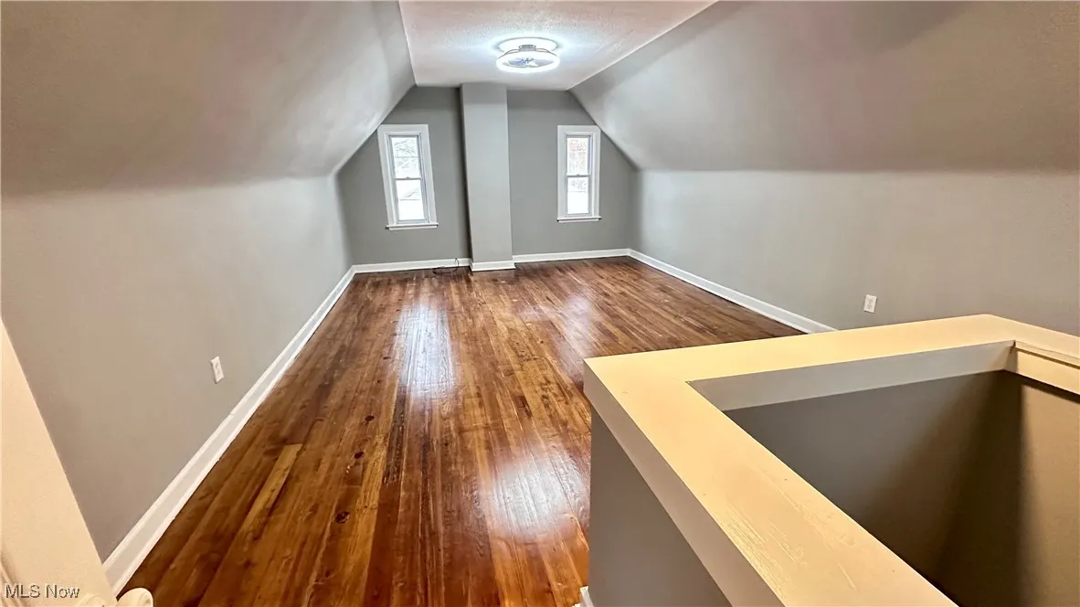 Additional living space with baseboards, dark wood-style flooring, and vaulted ceiling