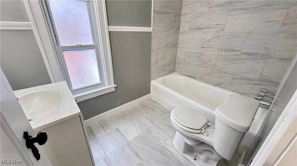 Bathroom with baseboards, vanity, toilet, and marble finish floor