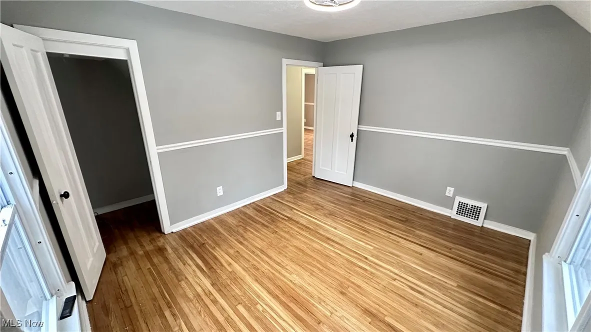 Unfurnished bedroom with baseboards, wood finished floors, and visible vents