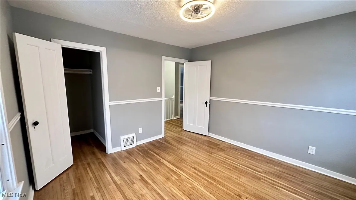 Unfurnished bedroom featuring baseboards, a closet, wood finished floors, and visible vents