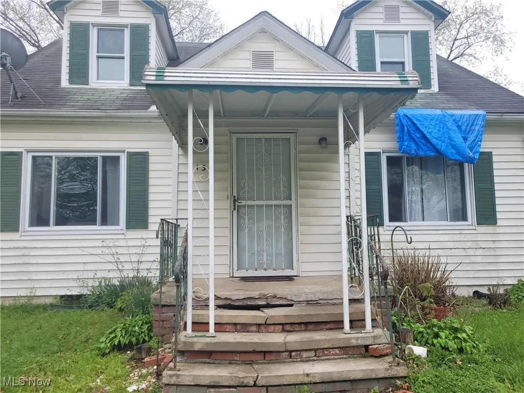 Property entrance featuring a shingled roof and a porch