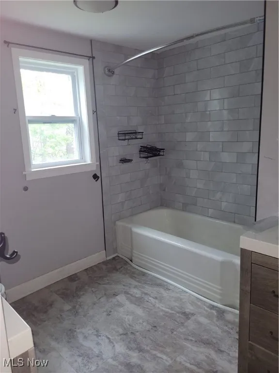 Full bath with vanity, baseboards, and tub / shower combination