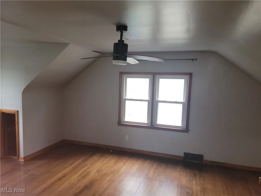 Additional living space featuring a ceiling fan, baseboards, lofted ceiling, and light wood-style floors