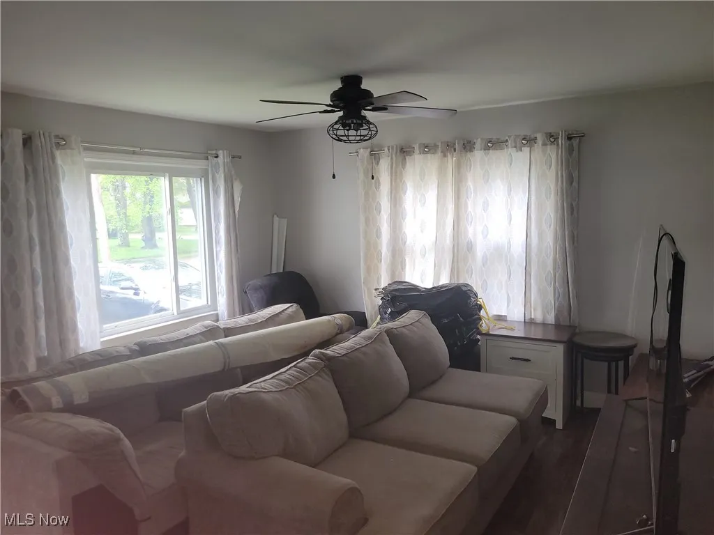 Living area featuring dark wood-type flooring and a ceiling fan