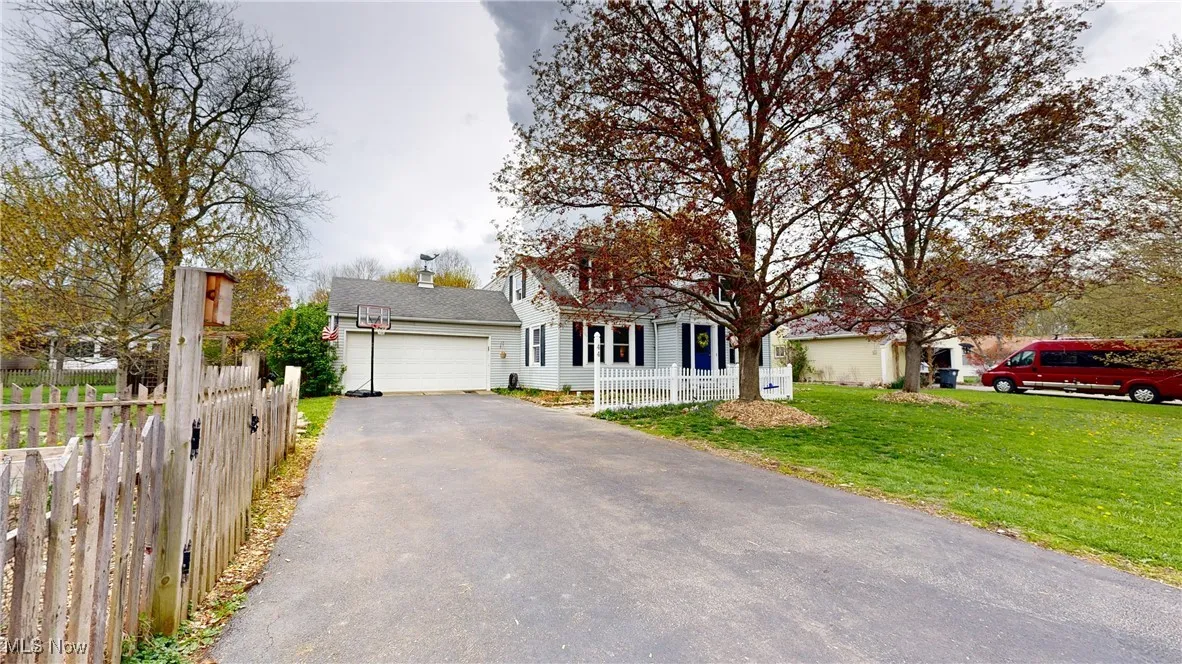 View of front of home with a front lawn, a garage, fence private yard, and aphalt driveway