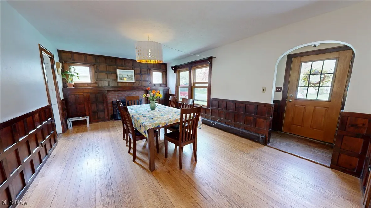 Dining space featuring a wainscoted wall, arched walkways, light wood-style flooring, and plenty of natural light