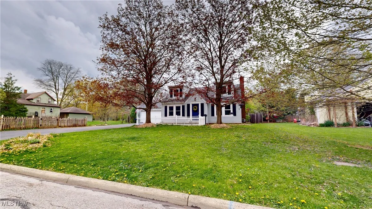 Cape cod house with a front yard, a garage, covered porch, driveway, and fence