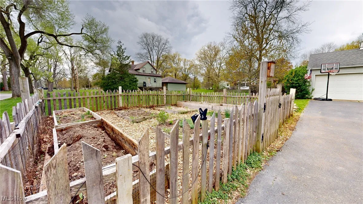 View of yard with a vegetable garden, a garage, driveway, and fence