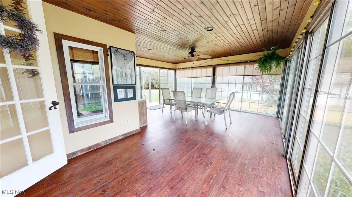 Sunroom with baseboards, outdoor dining space, wood finished floors, and a ceiling fan