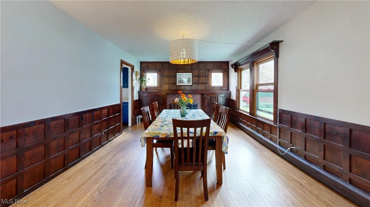Dining space featuring wood walls, a notable chandelier, a wainscoted wall, and light wood-style floors