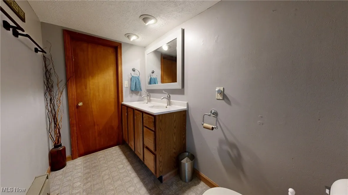Bathroom with tile patterned floors, a textured ceiling, vanity, and toilet