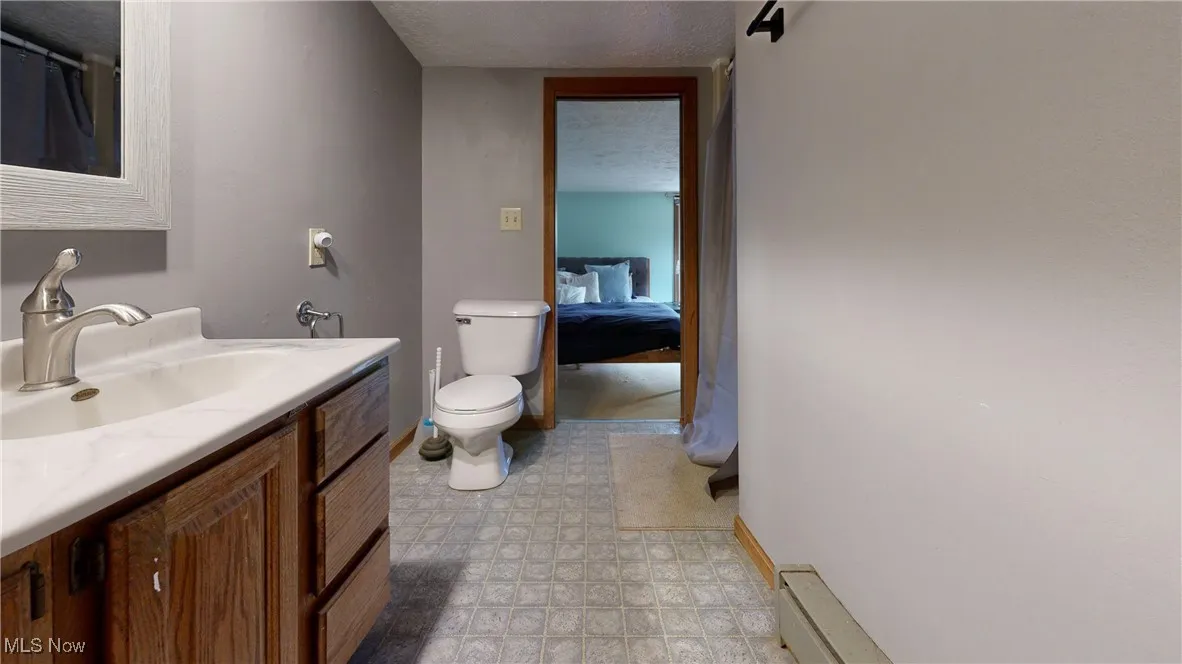 Bathroom featuring baseboards, toilet, and vanity