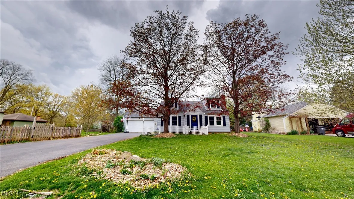 View of front facade with a garage, fence, driveway, and a front yard