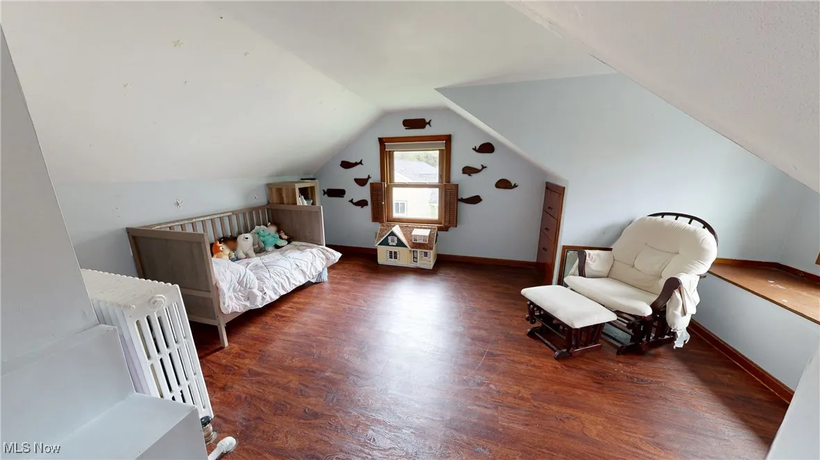 Bedroom with vaulted ceiling, wood finished floors, and baseboards