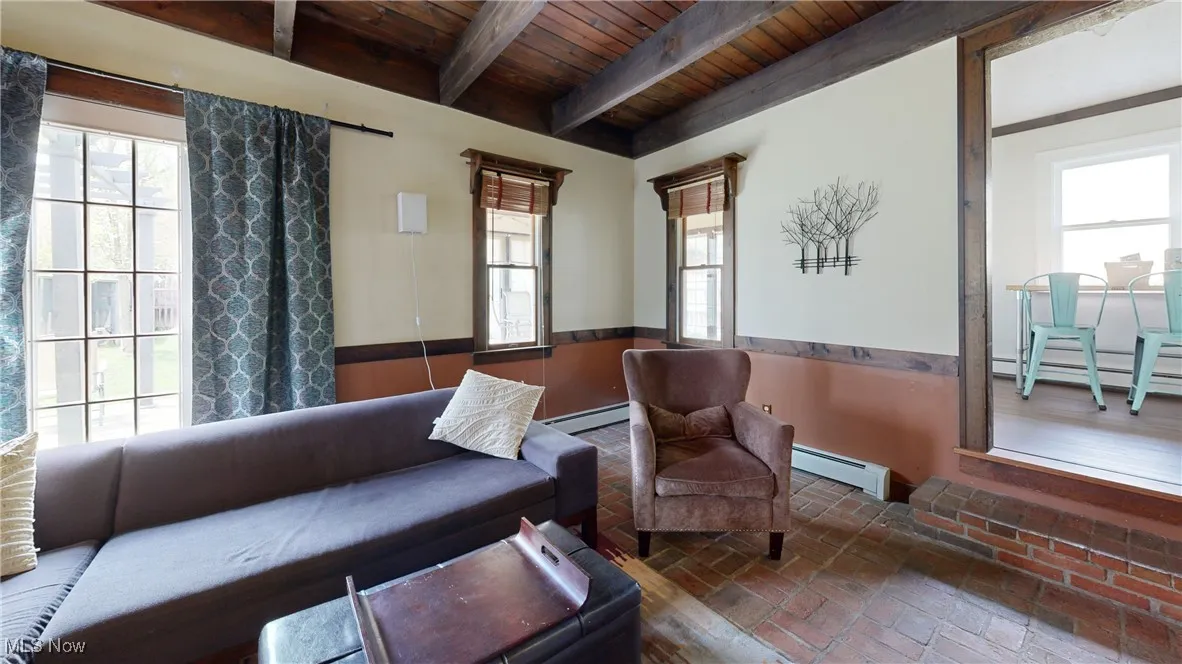 Living room with plenty of natural light, baseboard heating, brick floor, and wood ceiling